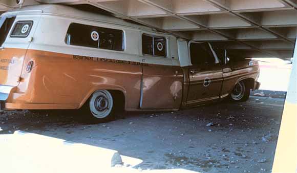 photo of ambulance squashed under the hospital building's garage roof