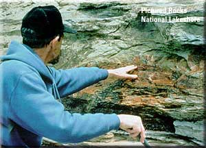A color photograph of a man looking at a rock face, Photo: National Park Service