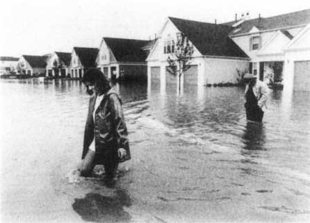 Photo of woman crossing flooded
		       street