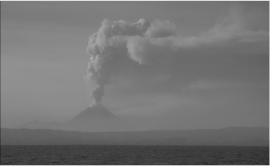 Figure 13. Kanaga Volcano in eruption as viewed from 42 km (26 mi) southeast of the volcano. Steam and ash plume rises approximately 3 km (9,840 ft) above the summit of the volcano and drifts to the east.
