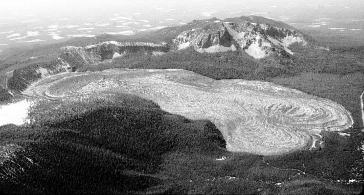 [Big Obsidian Flow (center), a 1,300-year-old lava flow, is the youngest product of
Newberry volcano. Paulina Peak (back center) forms the highest point on the rim of Newberry
Crater, a large caldera or volcanic depression at the summit of the volcano. (USGS photograph taken by William E. Scott, U.S. Geological Survey.)]