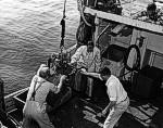 Geological Survey scientists aboard the Research Vessel GOSNOLD prepare a sampling bucket to go over the side.