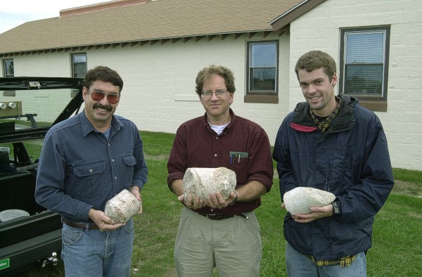 Photograph shows USGS and CH2M Hill geologists holding representative examples of bedrock cores.