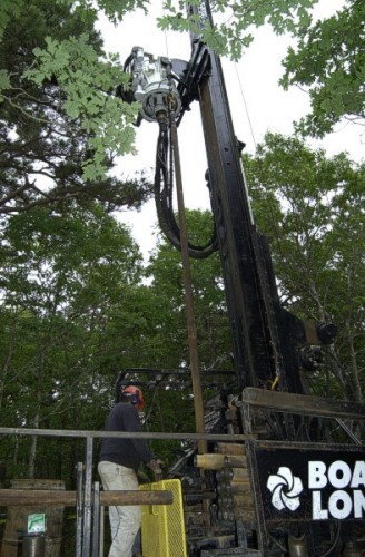 Photograph shows the sonic drill rig with the new section of drill casing in position for drilling.