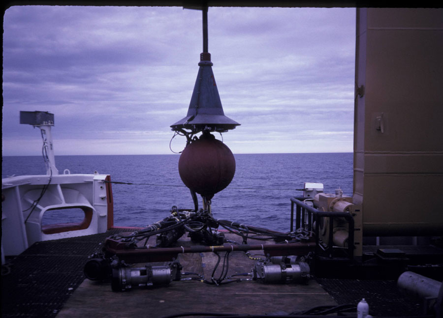 Photograph of the seismic system on deck, showing the air guns and frame, the towing weight, and the conical steel trumpet that protected the wet end connection point - Full Size