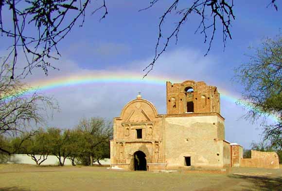photo of adobe building; rainbow in background