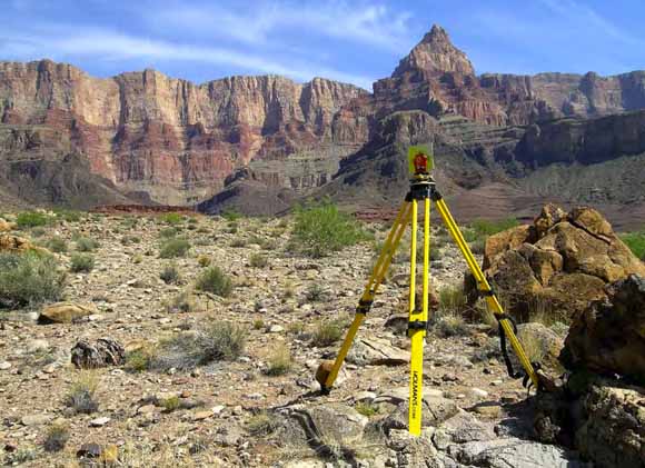 photo of surveying instrument on tripod, thousands of feet of cliffs in the background