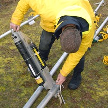 A USGS employee mounting a cantilever arm holding an Aquadopp and pinger onto a jet pipe.