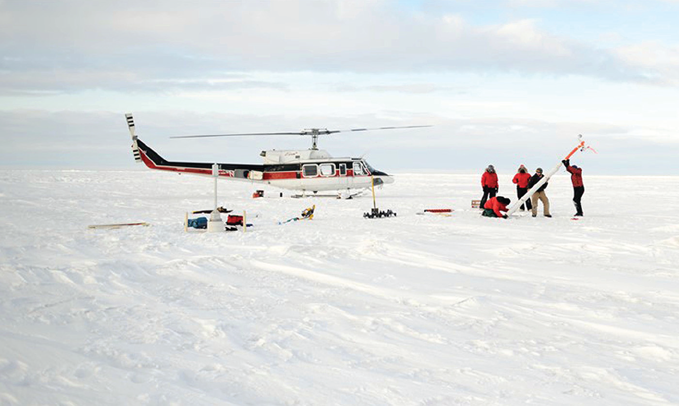 Photo shows plane on sea ice near scientists putting together a buoy.