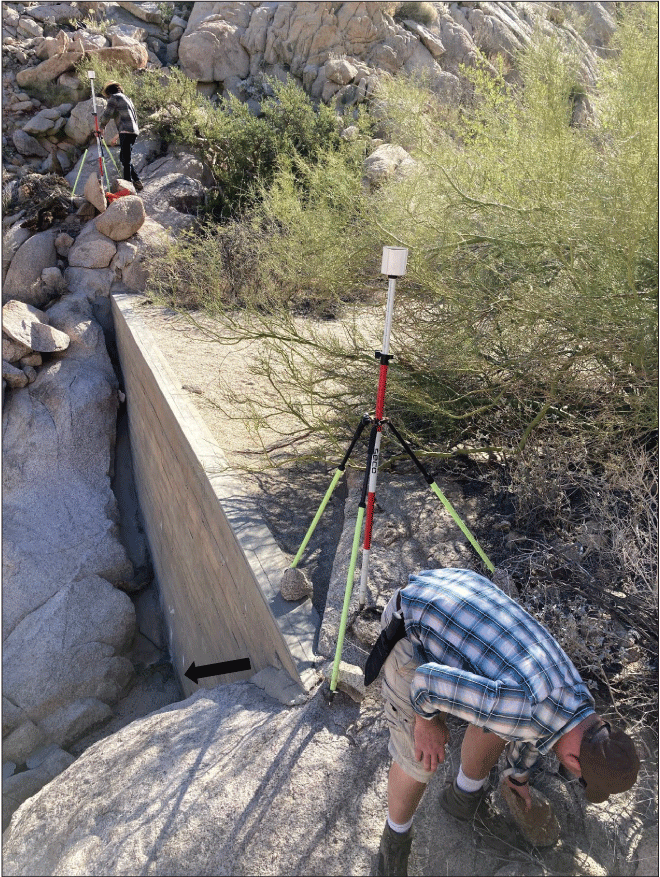 2.10. A different view of the concrete wall showing surveyors and equipment.