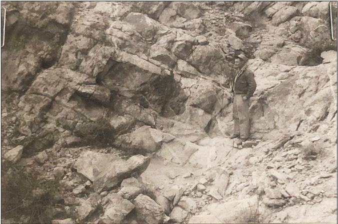 2.14. A person stands on a sloped rock wall.