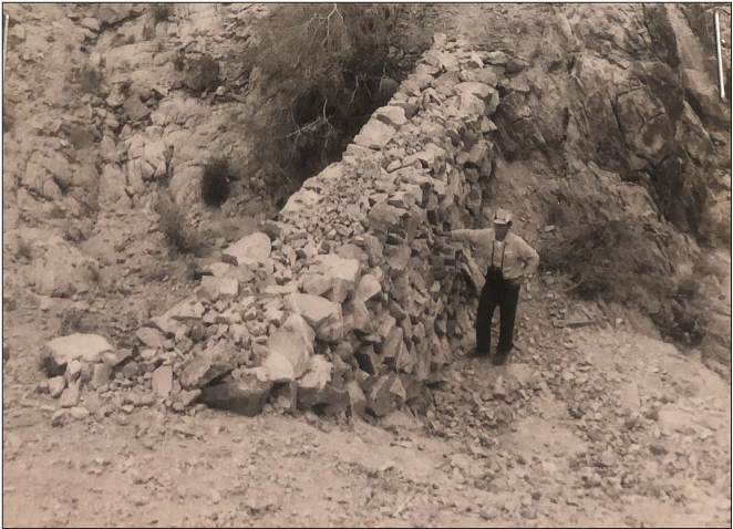 2.21. A person stands on the downstream side of a rock wall built in a channel.