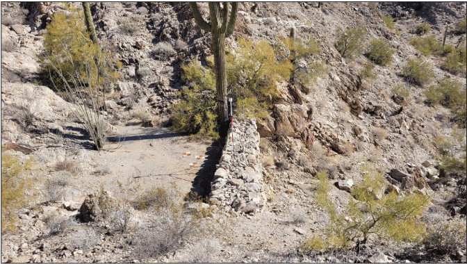 2.23. Sediment fill behind a constructed rock wall with sparse desert plants.