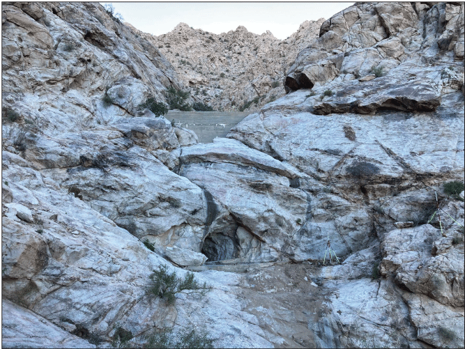 2.25. Rocky valley with a concrete wall in a channel and a steep drop downstream to
                  a circular opening cut into the rock.