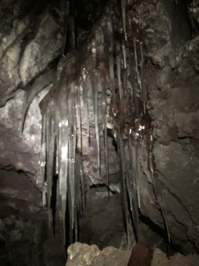 Thin, gray-black stalactites are shown.