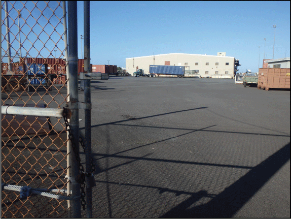 28. View of the asphalt loading area with warehouse in the background and shipping
containers and trucks on the asphalt.
