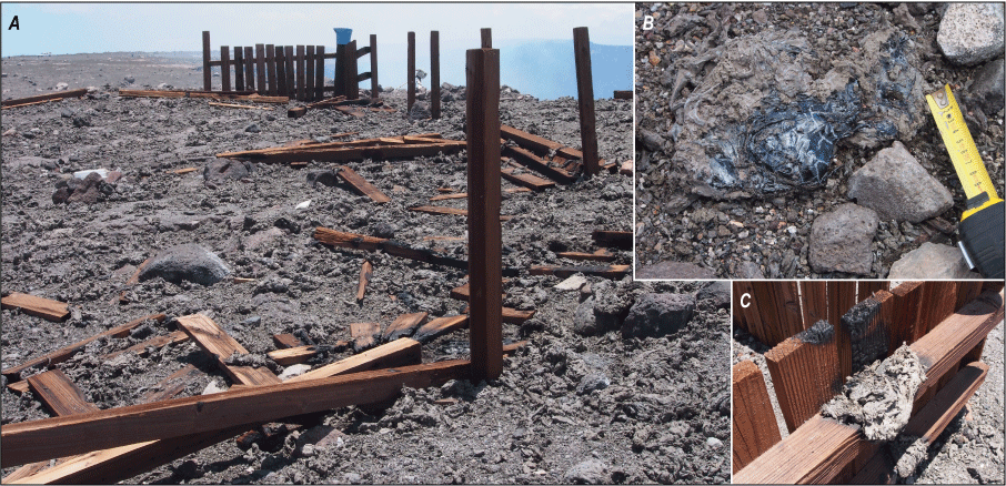 Alttext 11: Most of the wooden fencing from the overlook is gone, and the ground is
covered in gray tephra. Bits of fence are charred or burned.