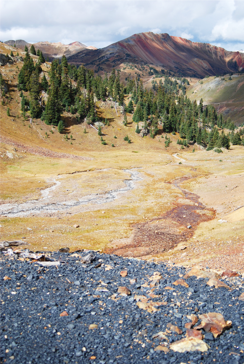 Photograph showing a rocky mountainside that has a streambed stained a darker color
                        because of acid drainage from a mine.