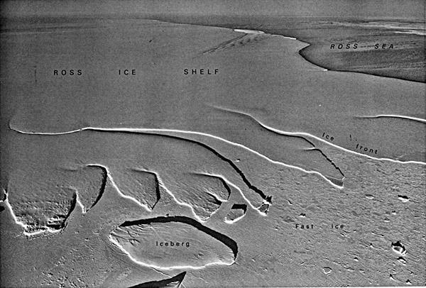 Figure 3-1.–Oblique aerial photograph of the ice front in Okuma Bay, eastern edge of the Ross Ice Shelf, Antarctica, on 22 October 1961. A tabular iceberg is visible in the bottom left-center foreground.