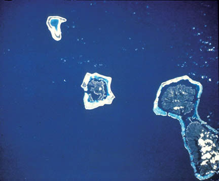 Figure 7-3.–Landsat image of four islands in the Society Islands of French Polynesia, about 200 kilometers northwest of Tahiti. Three of the islands are surrounded by fringing reefs with eroded extinct volcanoes within circumferential lagoons. Bora Bora is in the center. To its right is Taha’a and its neighbor to the south, Raiatea. Tupai, a small coral atoll, is in the upper left.