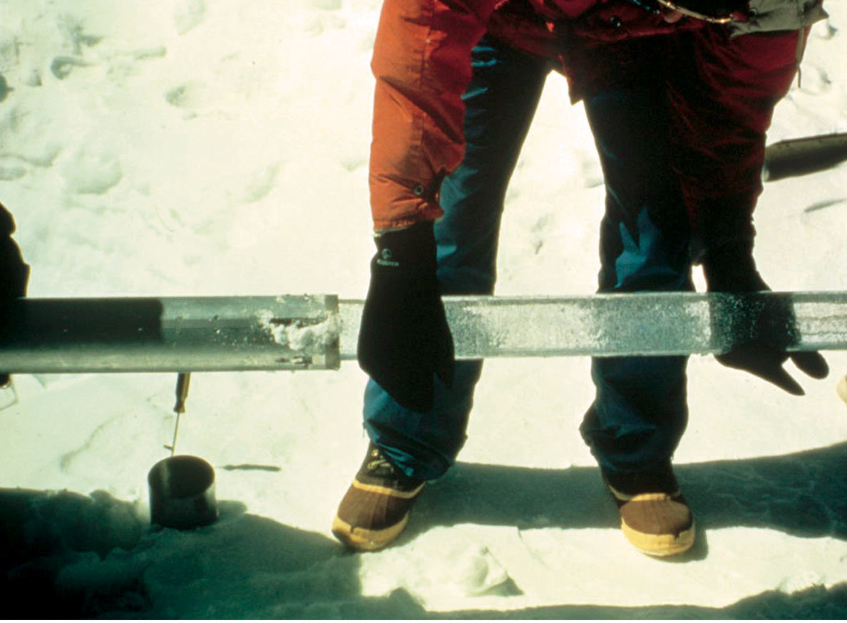 Figure 8-4.–Glaciologist extracting glacier ice core from a drilling barrel on the 6,100 meters col (pass) of Huascarán, Perú, in July 1993. Photograph by Lonnie G. Thompson, Byrd Polar Research Center, The Ohio State University, Columbus, Ohio.