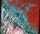Figure 2.—Landsat-5 Thematic Mapper (TM) image of Glacier National Park, Montana, acquired on 14 March 1991, showing snow-covered mountains. Clouds obscure parts of
the lower part of the image and appear as white or pink, whereas snow cover (including
snow-and-ice-covered lakes) is blue and non-snow-covered, vegetated land is reddish
orange. Landsat 5 TM false-color composite image 2569–17454, Path 69, Row 17, from
USGS EROS Data Center, Sioux Falls, S. Dakota. 
