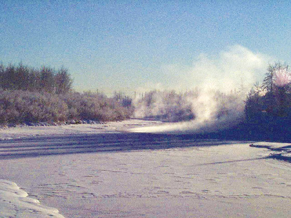 Figure 18, Heat and mass transfer from open water on the Chena River, Fairbanks, Alaska, are manifested as a fog plume on a cold (-25°C) morning, 5 March 2002. This reach of the river freezes only during the coldest weather because the water is artificially heated by a power plant located ~1 km upstream (into the page). Photograph by Martin O. Jeffries, Geophysical Institute, University of Alaska Fairbanks.