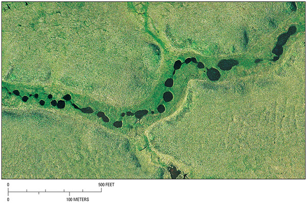Figure 23.—Vertical aerial photograph of beaded stream channels resulting from melting of ice wedges and thawing of surrounding ice-rich permafrost.
The photograph was taken in summer 2004 south of the town of Nuiqsut, northern Alaska, by M.T. Jorgenson, ABR, Inc., Fairbanks, Alaska.  