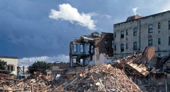 photo of damaged and destroyed three-story buildings with rubble in the foreground