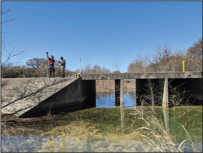 Figure 2. Photograph shows U.S. Geological Survey field crew performing a hydraulic-structure
                        survey of a culvert at Utopia, Texas.