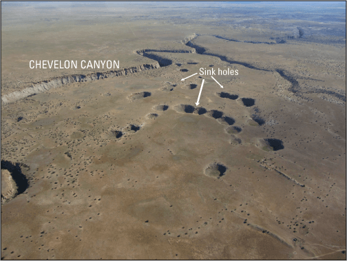 Figure 23.	Oblique aerial photograph looking north at McCauley Sinks and Chevelon
                        Canyon southeast of Winslow, Arizona. The land surface is very flat in this area and
                        the sinkholes appear as circular pits in the surface. The sinkholes are grouped closely
                        together to the east of Chevelon Canyon.