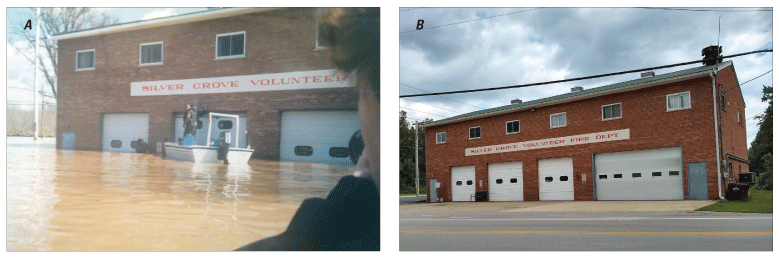 In photograph of flood, one person is on a boat and another is torso-deep in water.
               Water level is about half the height of the fire station’s bay doors.