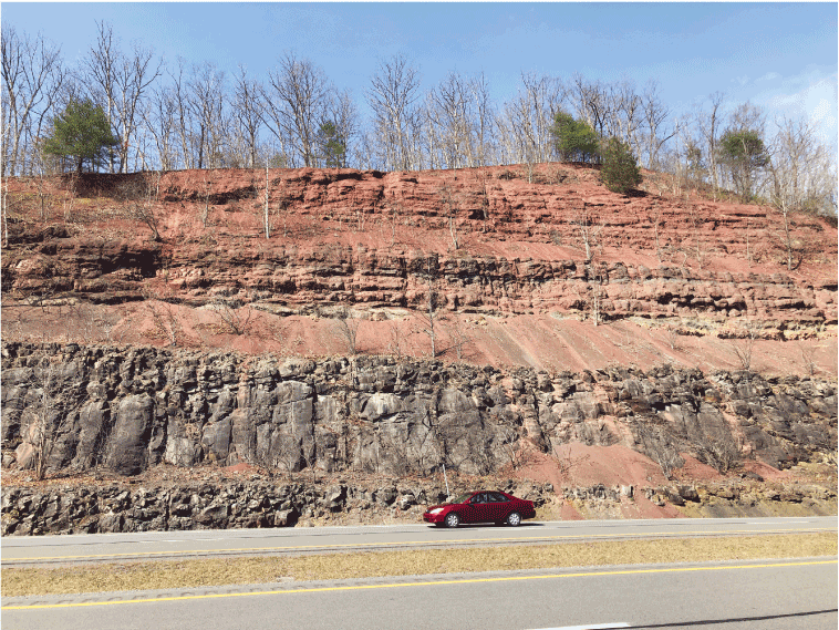 Vertical and horizonal striations are visible within the exposed cross-section of
                              rock layers within the hillside.