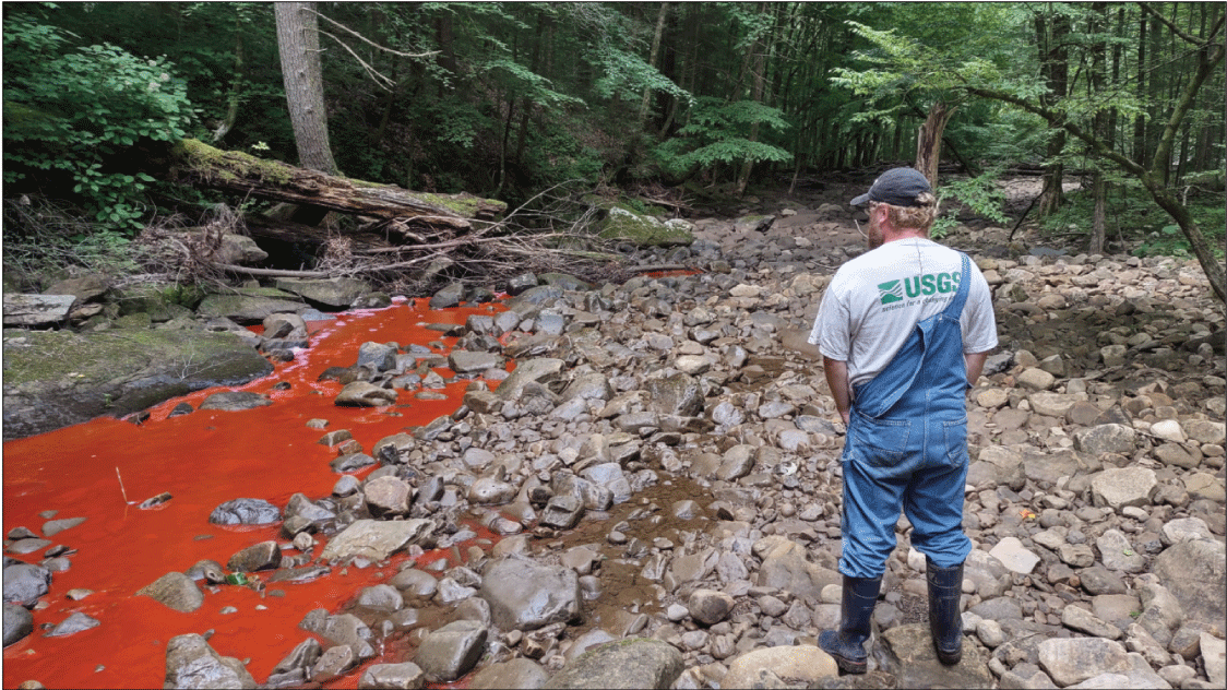 Alt text: Red rhodamine wt dye in shallow stream.