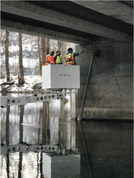 Photograph showing U.S. Geological Survey (USGS) and Idaho Transportation Department
                           (ITD) personnel inside the Under Bridge Inspection Truck (UBIT) during the sonar device
                           installation at bent two on ITD bridge structure 30730 on January 30, 2020. The site
                           is located with USGS station Saint Joe River at Calder, Idaho (USGS station number
                           12414500)