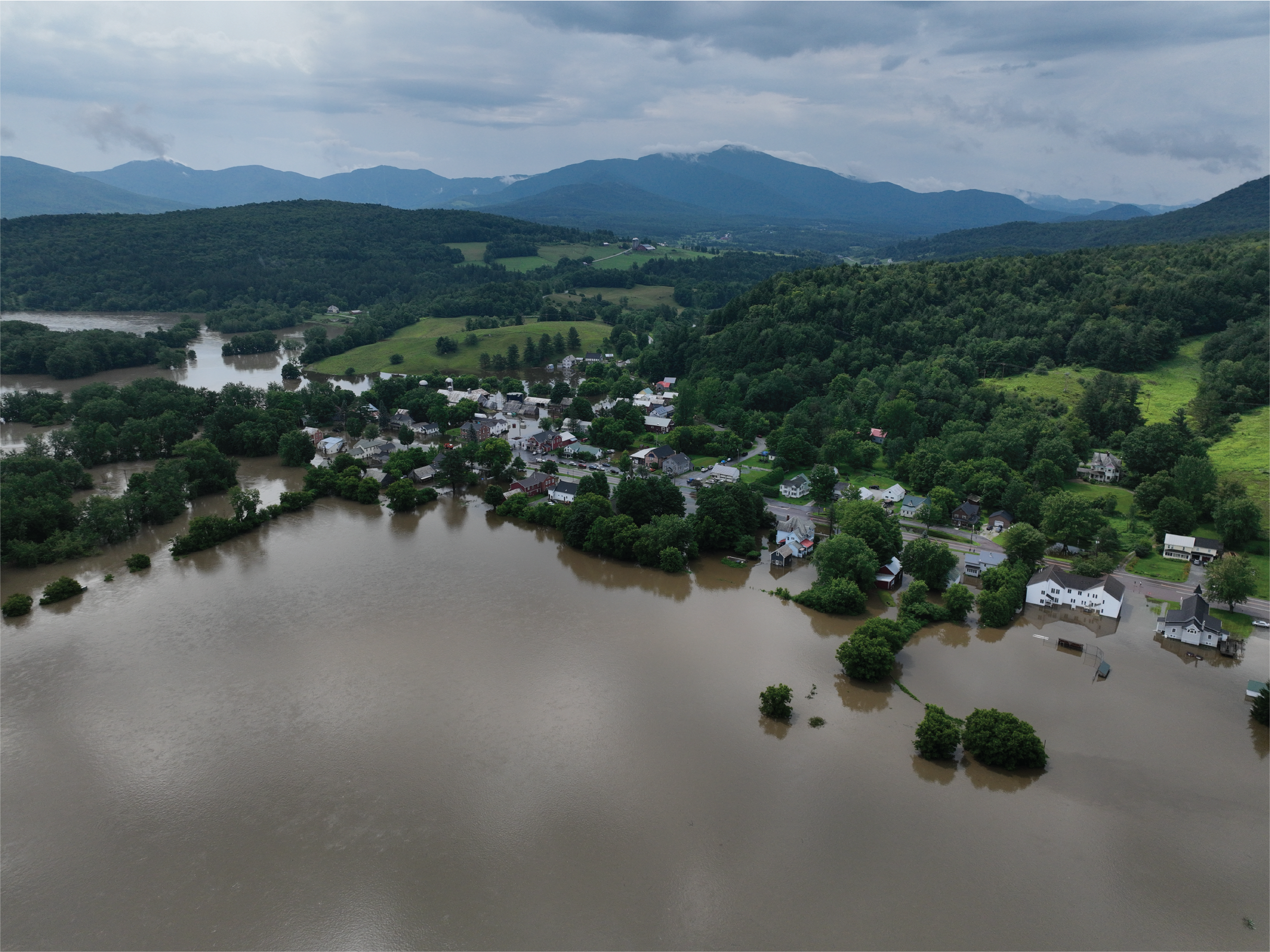 Arial image of a large expanse of floodwater, overtaking vegetation and houses.