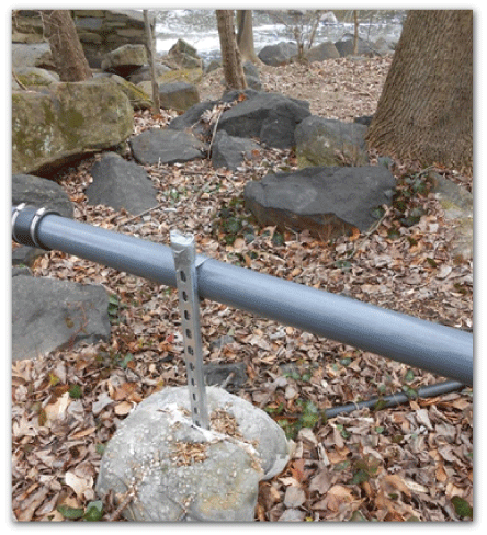Image of steel bar embedded in concrete supporting the intake line above the ground.