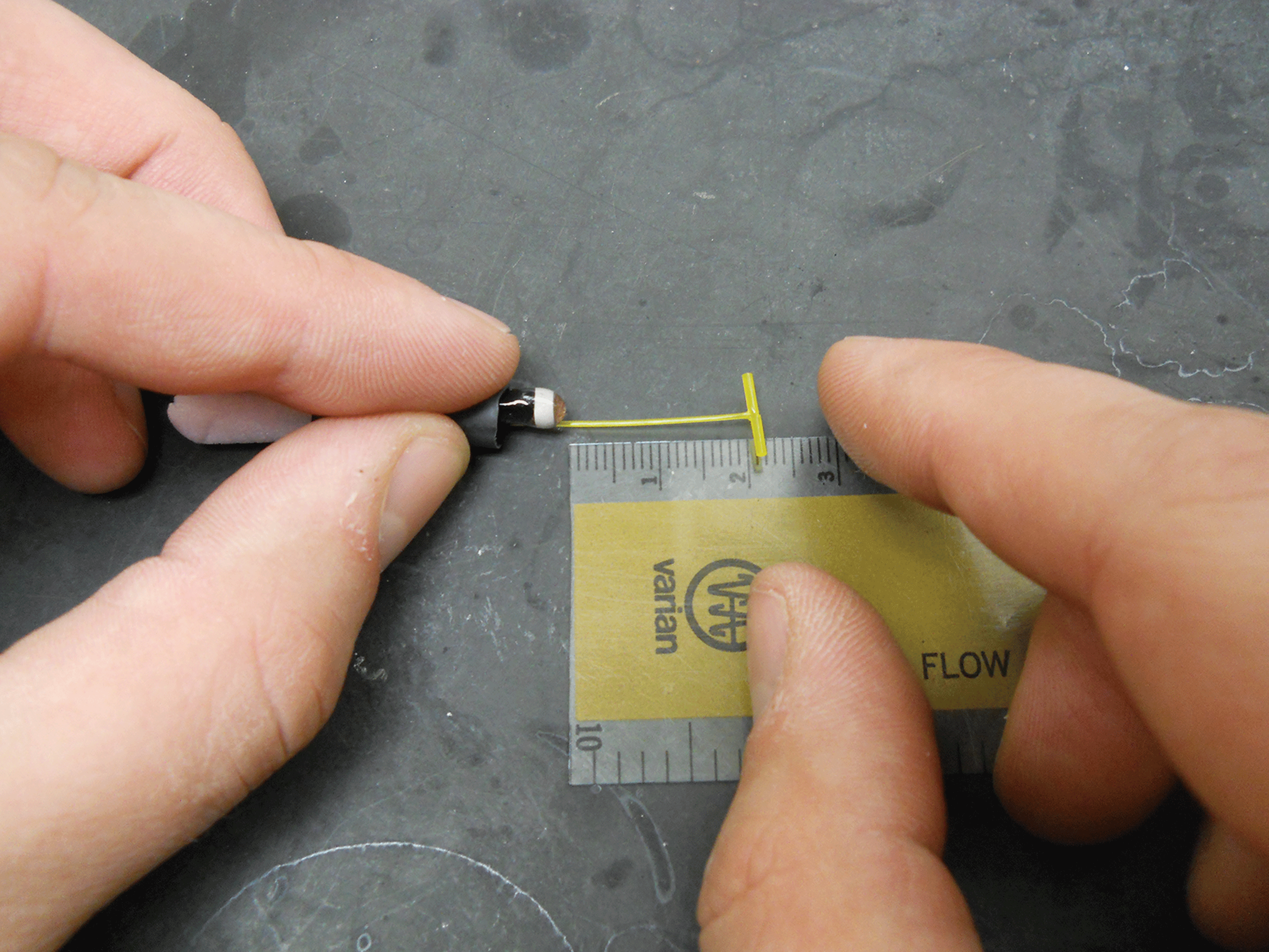 Photograph showing the T-bar end of the tag being pulled 20 millimeters from the end
                        of the shrink tubing.