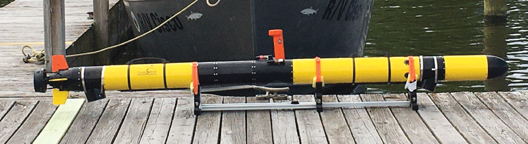 Photograph showing a cylindrical yellow and black robot carrying the Autonomous Benthic
Imaging and Surveying System version 1 (ABISS1) resting on a wooden dock.